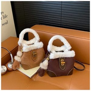 Détail de sacs seaux camel et marron avec bordure en fausse fourrure blanche et charms bois