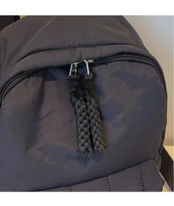 Detail of dual metal zippers with extended black woven pullers on a matte nylon backpack