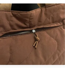Detail of smooth zipper on coffee quilted nylon tote bag with braided rope puller