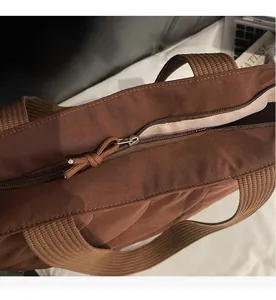 Close-up of smooth zipper closure and woven strap on brown padded tote bag