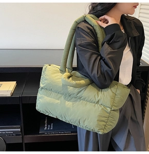 Detailed texture of a large quilted down tote bag with soft padded straps in sage green