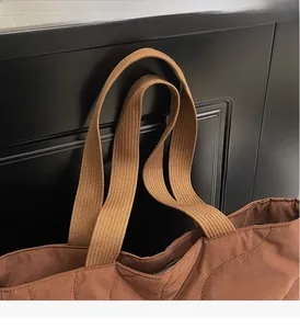 Detail of coffee brown quilted tote bag with wide woven handle and wavy stitch pattern