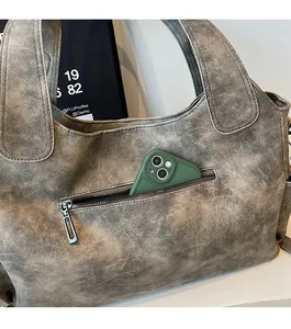 Close-up of anti-theft zipper pocket on gray matte texture tote bag holding a phone