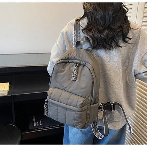 Detail of grey quilted nylon backpack with lettered straps and fluffy puffer texture