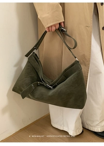 Detail of olive green suede tote bag with decorative buckle and adjustable shoulder strap