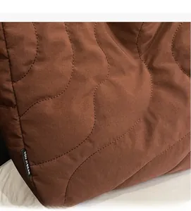 Detail of brown quilted wave pattern fabric and brand label on a soft tote bag