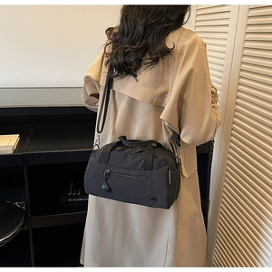 Detail showing the adjustable shoulder strap and front zipper of the black nylon crossbody bag
