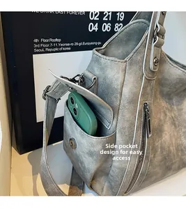 Macro detail of tote bag magnetic side pocket with white stitching and smartphone inside