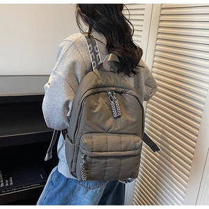 Detail of grey quilted nylon backpack with padded texture and branded shoulder straps
