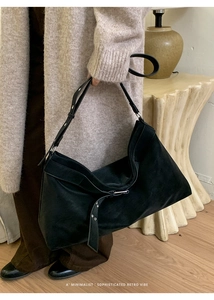 Detail shot of the black suede tote bag featuring a decorative metal buckle and strap