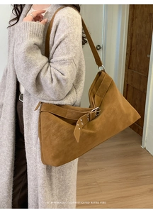 Detail of a brown suede hobo bag featuring a retro buckle strap and pleated texture