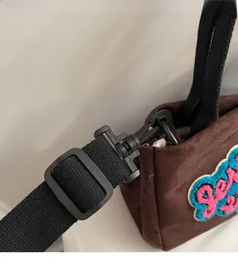 Détail du crochet noir durable et du tissu en peluche marron de ce sac bandoulière