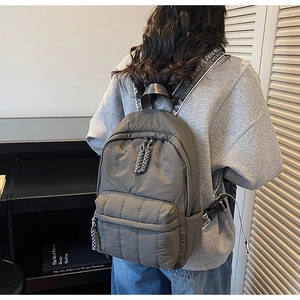 Macro detail of grey quilted backpack featuring Have A Nice Day text on straps