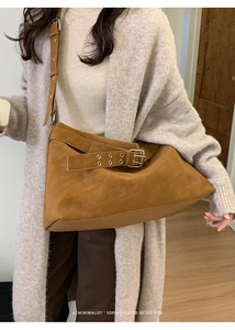 Detail of retro suede tote bag with decorative buckle and metal eyelets on wide strap