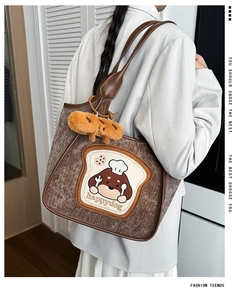 Detail of brown corduroy tote bag with cute dog patch and croissant plush charm