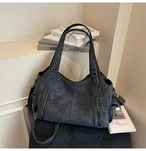 Detail of dark grey retro tote bag featuring decorative zippers and functional side pockets