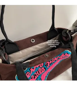 Détail d'un sac en peluche marron avec fermoir magnétique, poche zippée et doublure chevron