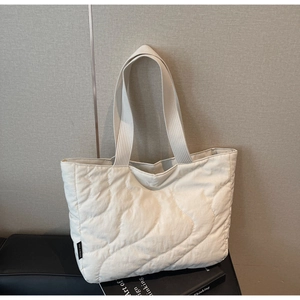 Close-up of cream quilted tote bag showing detailed wave stitching and shoulder strap