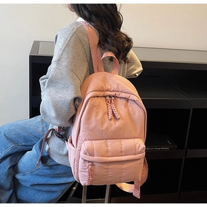 Detail of pink quilted backpack with woven rope zippers and wide fashion straps