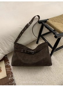Detailed close-up of dark brown suede tote bag with silver metal buckles and adjustable strap