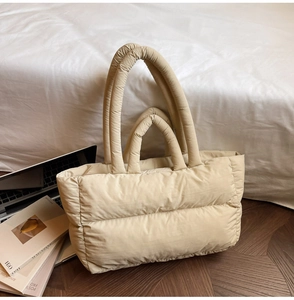 Close-up of beige quilted down tote bag with double handles in a cozy indoor setting