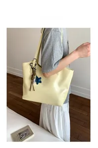 Détail du sac cabas crème avec pendentif étoile bleue et nœud décoratif en cuir