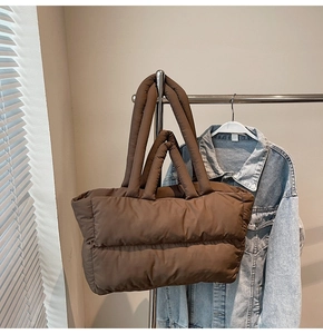 Detail of dark brown quilted puffer tote bag featuring soft padded texture and top handles