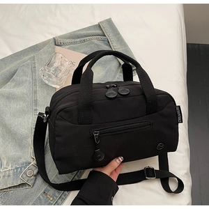 Detailed view of black nylon crossbody bag featuring adjustable strap and woven brand tag