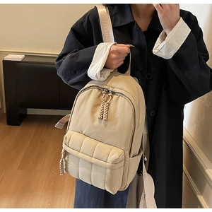 Detail of beige quilted nylon backpack with braided rope zipper and fashion strap