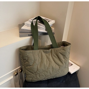 Detail of olive green quilted tote bag with wave stitching and branded side label