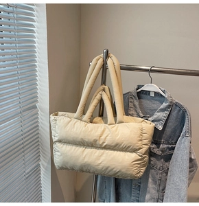 Detail of beige quilted puffer tote bag with wide padded handles for shoulder carry