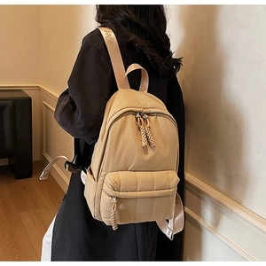 Detail view of khaki nylon backpack featuring fashion straps and front zipper pocket