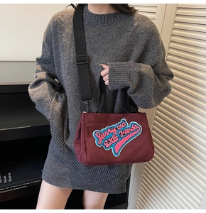 Détail du sac à bandoulière en velours bordeaux avec broderie bouclée colorée élégante