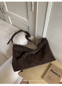 Detail of dark brown suede tote bag featuring metallic grommets in a retro style