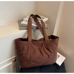 Detail of brown quilted nylon tote bag featuring wavy stitching and durable wide handle