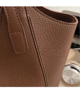 Close-up of brown litchi pattern leather tote bag showing fine stitching and texture