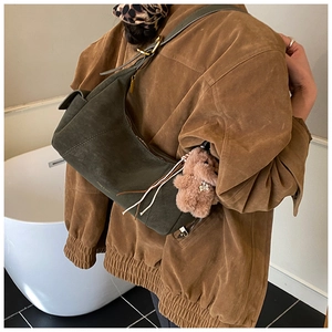 Dark green suede shoulder bag with gold logo and cute plush bear charm on model
