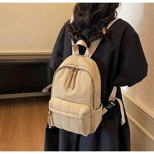 Close-up of the beige quilted backpack featuring woven zipper pulls and fashion strap detail