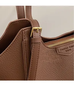 Detail of brown litchi pattern leather tote with golden hardware and fine stitching