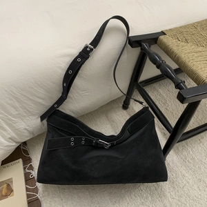 Detail of black suede tote bag featuring silver eyelet buckles and smooth shoulder strap
