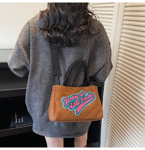 Détail du sac bandoulière en peluche marron avec broderie Jerry et large sangle noire