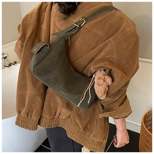 Detail of vintage olive green shoulder bag with side buckle and pink plush charm