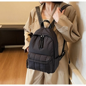 Detail of black quilted nylon backpack featuring branded straps and multiple pockets