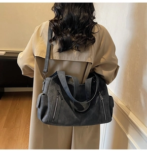 Detail of dark gray retro tote bag with multi-pocket design on casual trench coat