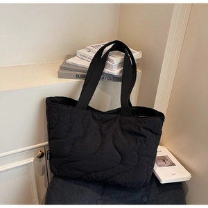 Detailed view of wave quilted black tote bag showing durable texture and webbing handles