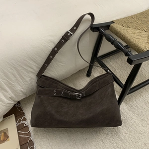 Detailed close-up of the vintage brown suede tote bag with metal eyelet strap on a rug