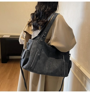 Model wearing dark grey vintage soft leather tote bag with multi-zipper pockets