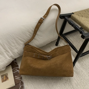 Detailed view of brown suede tote bag with metal grommets and vintage buckle accents