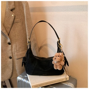 Detail of black matte hobo bag with gold hardware and a cute brown plush bear charm