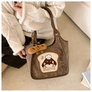 Detail of brown corduroy tote bag with cute cartoon dog embroidery and plush bread pendant